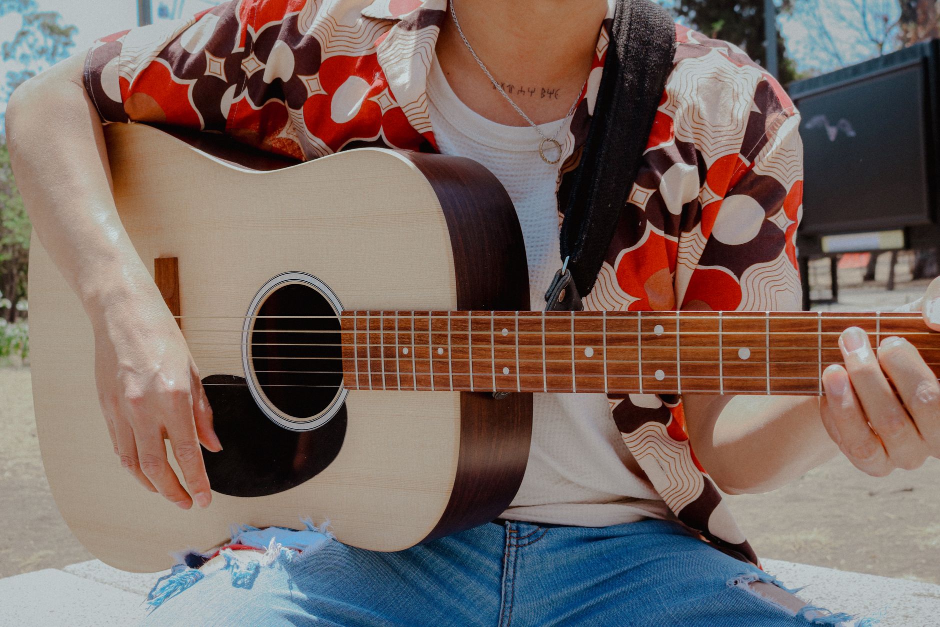 Comprendre ce que « apprendre la guitare » veut dire vraiment — personne jouant de la guitare acoustique dehors